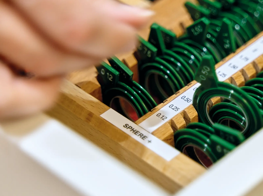 Detalle de mano con lentes de graduación intercambiables / Servicio de optometría ÓPTICA ALAMEDILLA